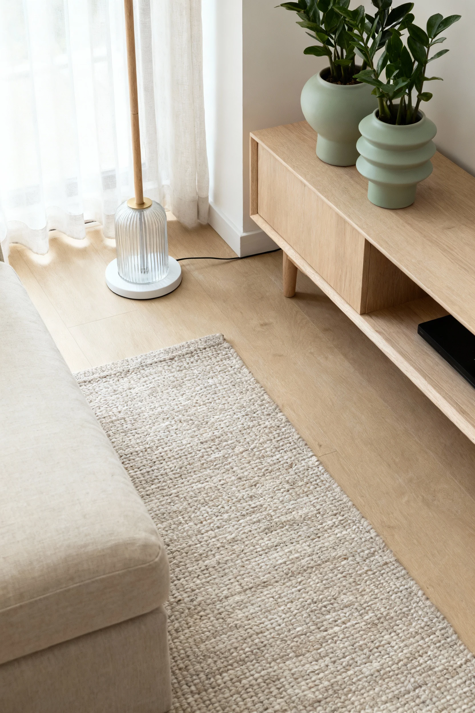 2. Photorealistic overhead detail shot capturing a calm Scandinavian setup: the edge of a linen sofa over a neutral flat