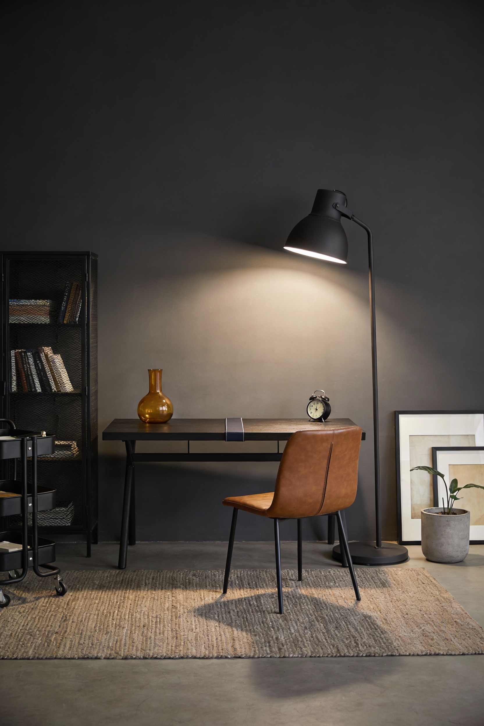 Medium straight-on shot of a moody industrial desk against a charcoal accent wall: dark BEKANT desk with a thin runner, 