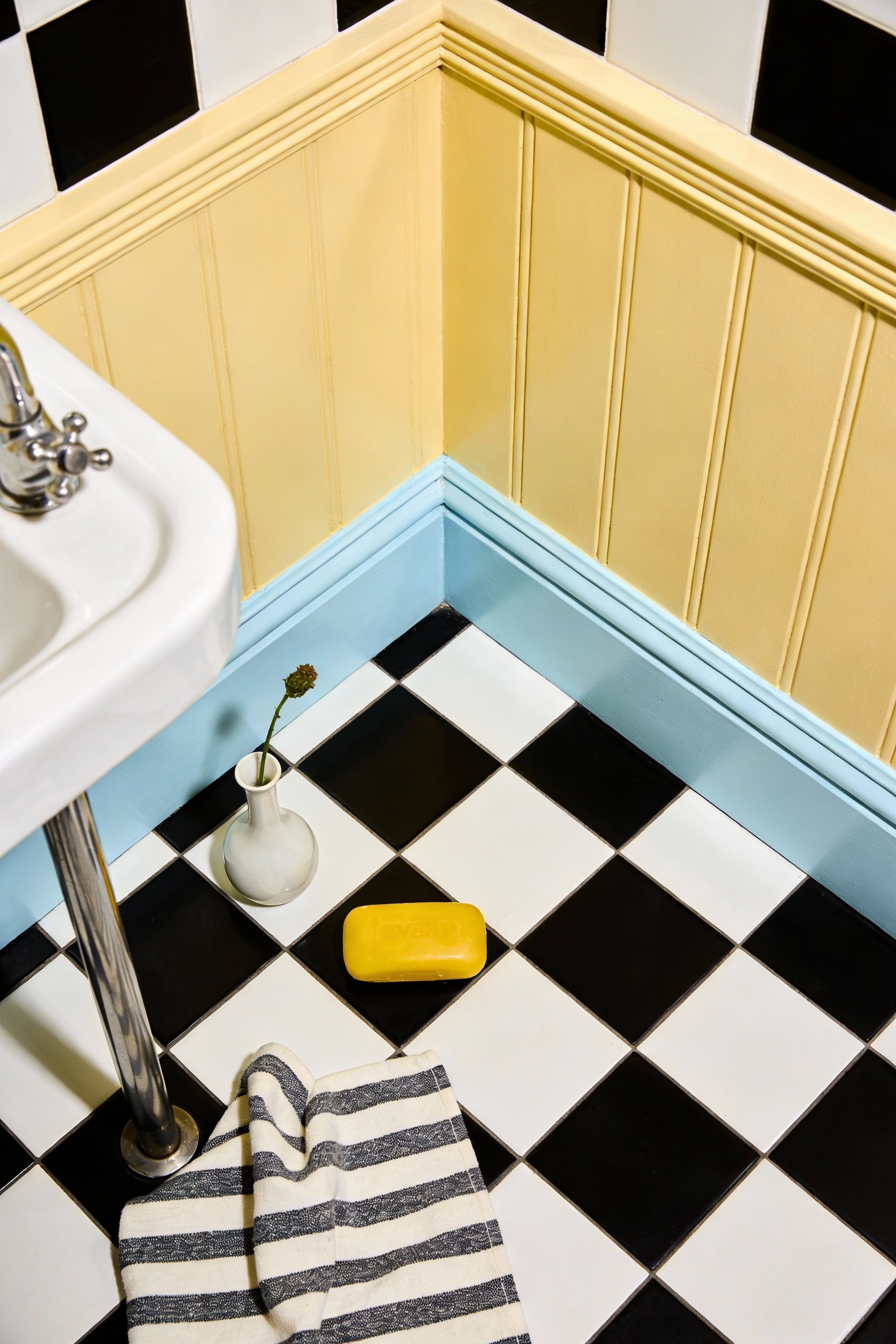 Overhead photorealistic detail shot focused on the playful vintage cloakroom floor and styling: crisp black-and-white ch