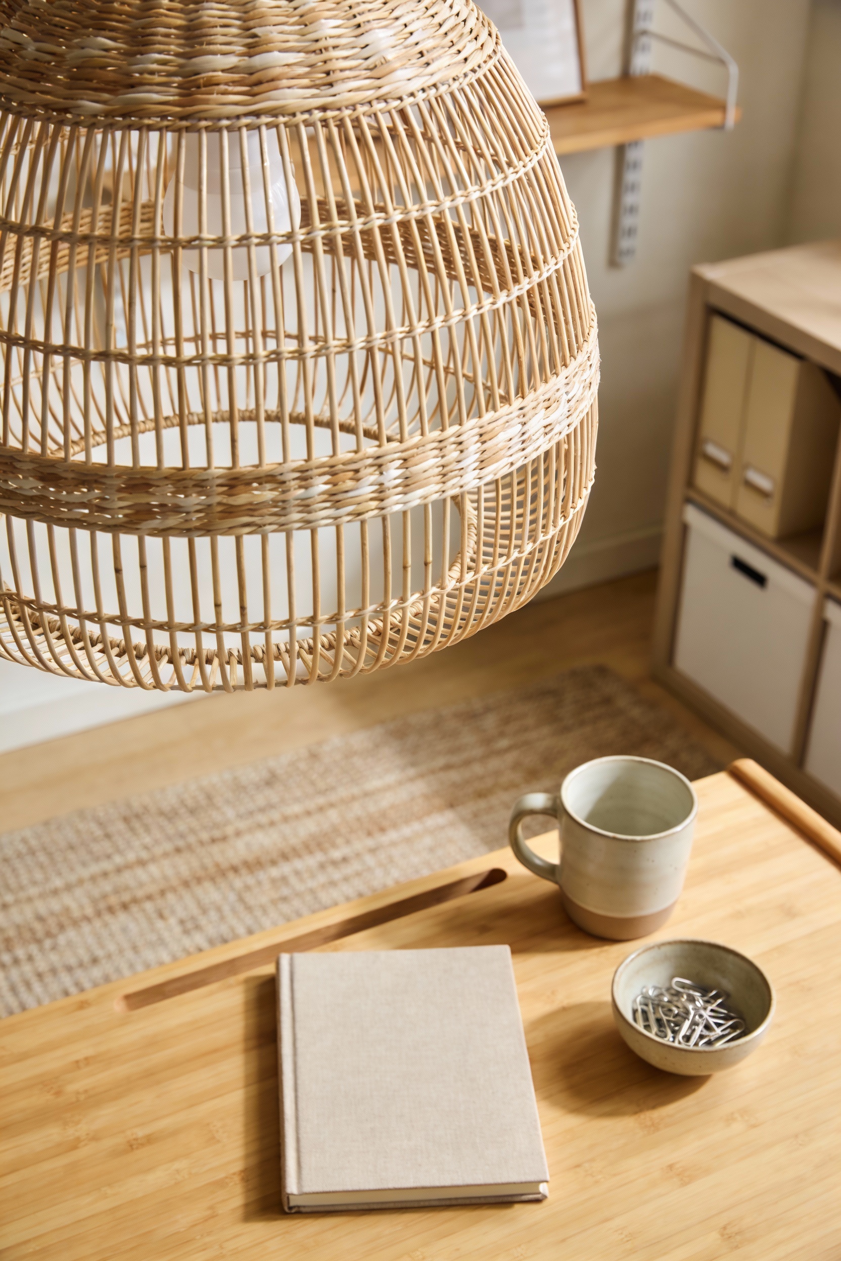 Close-up detail in a Japandi workspace: bamboo LILLÅSEN desk surface with linen notebook, stoneware cup, and small bowl 